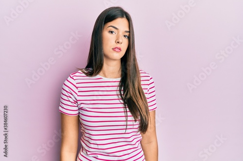 Fotografie Young brunette woman wearing casual clothes over pink background relaxed with serious expression on face
