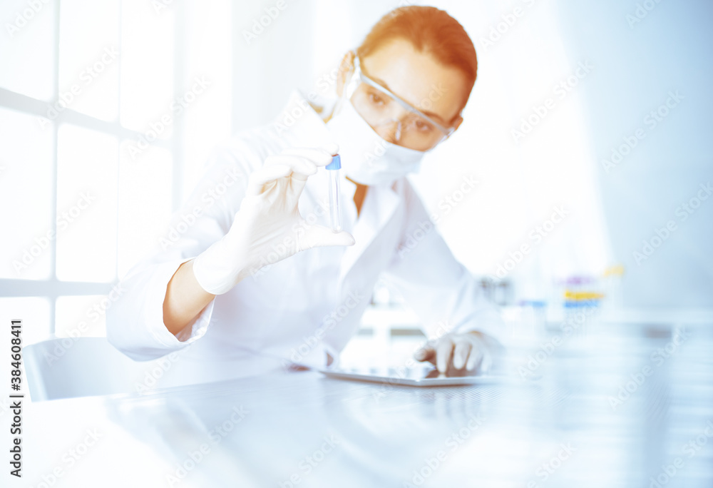Female laboratory assistant analyzing a blood sample at hospital. Medicine, health care and researching concept Female laboratory assistant analyzing a blood sample at hospital. Medicine, health care and researching concept