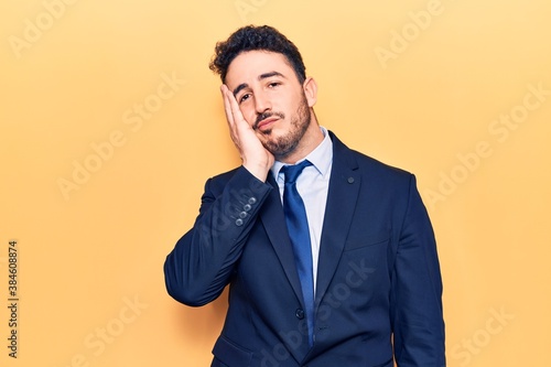 Young hispanic man wearing suit thinking looking tired and bored with depression problems with crossed arms.