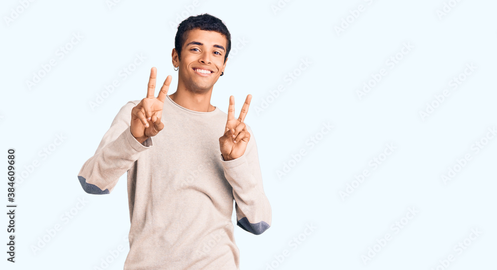 Young african amercian man wearing casual clothes smiling looking to the camera showing fingers doing victory sign. number two. Young african amercian man wearing casual clothes smiling looking to the camera showing fingers doing victory sign. number two.