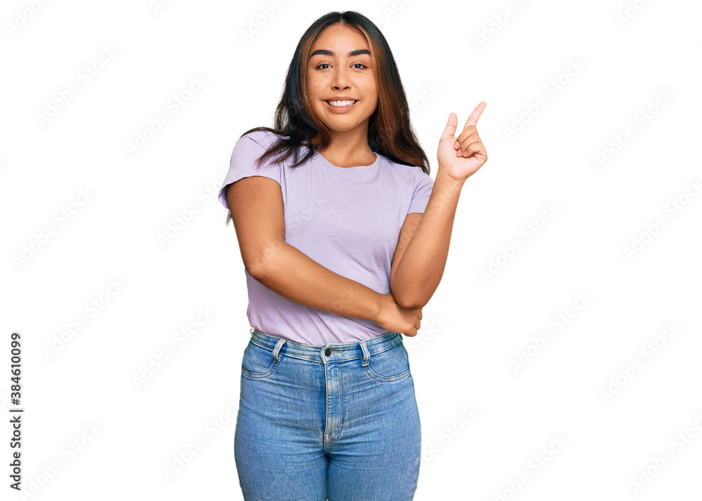Young latin woman wearing casual clothes with a big smile on face, pointing with hand and finger to the side looking at the camera.