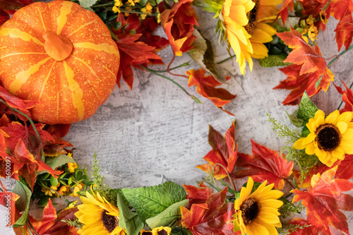 Autumn background: orange pumpkin, yellow sunflowers, orange and red leaves, floral frame for design. Soft focus