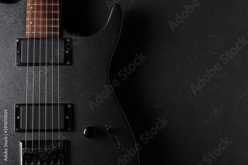Gray electric guitar close-up on a dark concrete background. Top view and place for your text on the right.