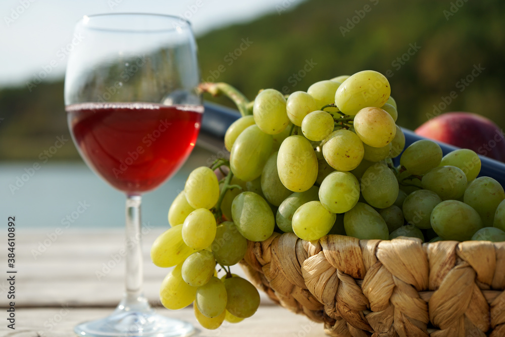 fruit basket and a glass of wine on the wooden picnic pier fruit basket and a glass of wine on the wooden picnic pier
