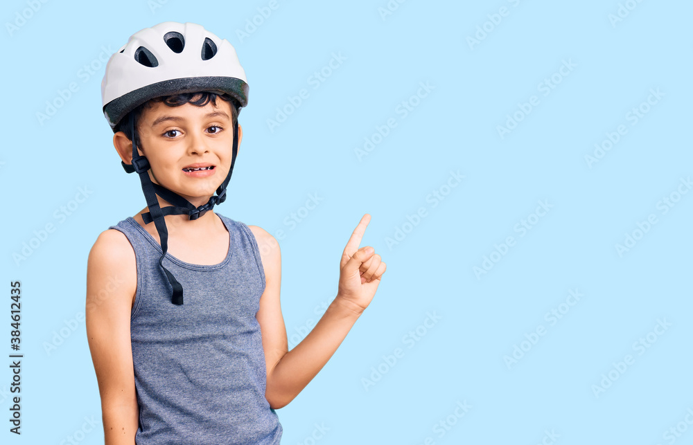 Little cute boy kid wearing bike helmet smiling happy pointing with hand and finger to the side Little cute boy kid wearing bike helmet smiling happy pointing with hand and finger to the side