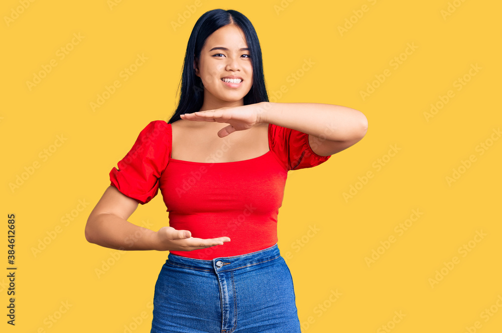 Young beautiful asian girl wearing casual clothes gesturing with hands showing big and large size sign, measure symbol. smiling looking at the camera. measuring concept. Young beautiful asian girl wearing casual clothes gesturing with hands showing big and large size sign, measure symbol. smiling looking at the camera. measuring concept.