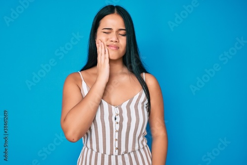 Young beautiful asian girl wearing casual clothes touching mouth with hand with painful expression because of toothache or dental illness on teeth. dentist