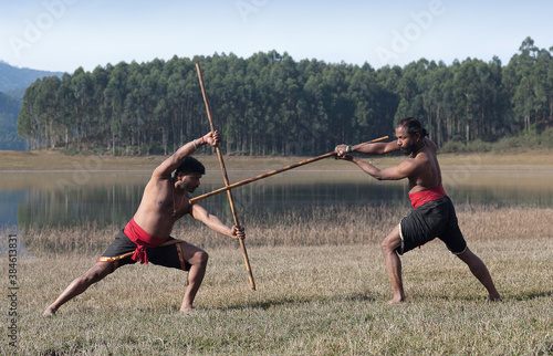 Indian fighters with bamboo sticks performing Kalaripayattu Marital art demonstration outdoors in Kerala state, South India photo