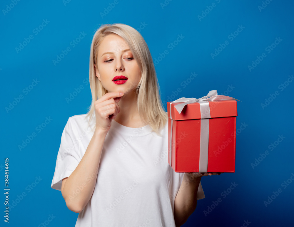 girl in white t-shirt with present box on blue background girl in white t-shirt with present box on blue background