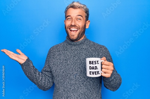 Valokuva Handsome blond man drinking cup of coffee with best dad ever message over blue b