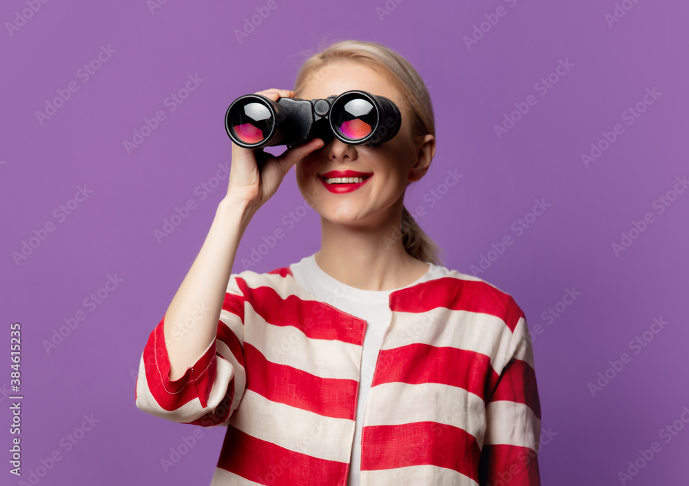 Beautiful blonde in red jacket with binoculars on puprle background Beautiful blonde in red jacket with binoculars on puprle background