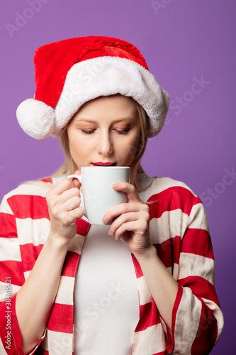 Beautiful blonde in red jacket and Christmas hat on purple background