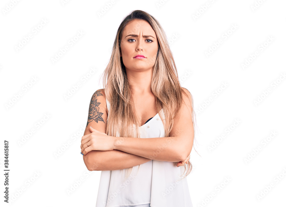 Young beautiful blonde woman wearing sleeveless t-shirt skeptic and nervous, disapproving expression on face with crossed arms. negative person. Young beautiful blonde woman wearing sleeveless t-shirt skeptic and nervous, disapproving expression on face with crossed arms. negative person.