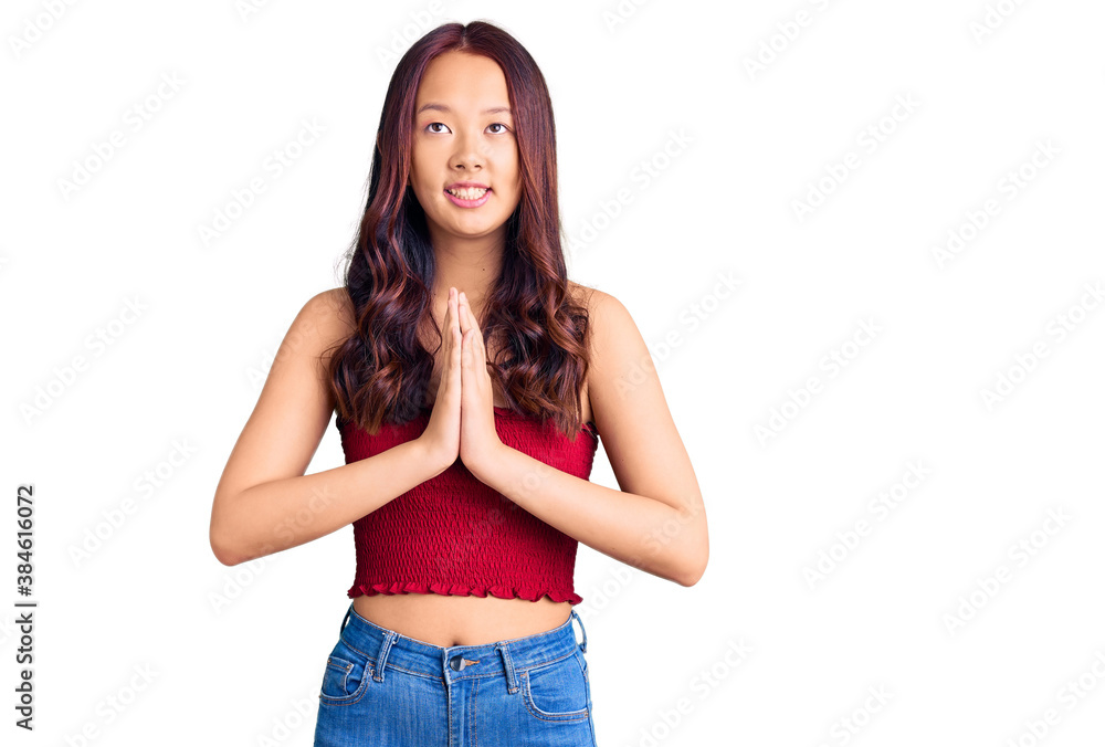 Young beautiful chinese girl wearing casual clothes begging and praying with hands together with hope expression on face very emotional and worried. begging. Young beautiful chinese girl wearing casual clothes begging and praying with hands together with hope expression on face very emotional and worried. begging.