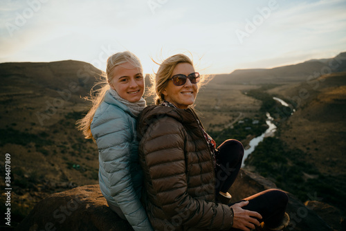 Fotografie, Tablou Caucasian mother and daughter bonding while watching beautiful sunset on top of