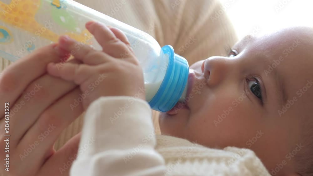 Closeup view of mother feeding her baby milk from bottle Closeup view of mother feeding her baby milk from bottle