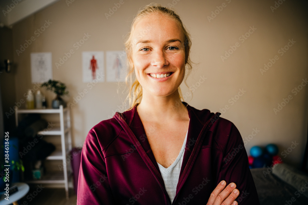 Beautiful smiling physiotherapist happily standing cross- armed in pilates studio Beautiful smiling physiotherapist happily standing cross- armed in pilates studio