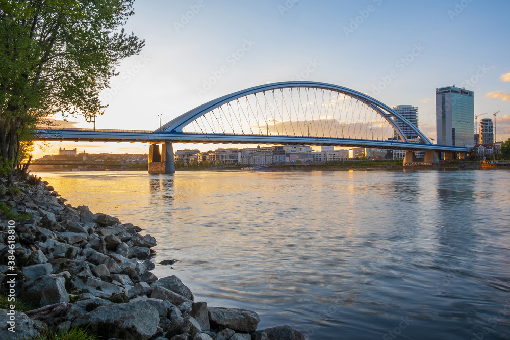 Obraz premium 2020: Long exposure Apollo bridge over river Danube in Bratislava, Slovakia. Sunset, golden hour, dramatic skies. High rise buildings, travel destination