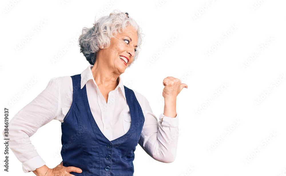 Senior grey-haired woman wearing casual clothes smiling with happy face looking and pointing to the side with thumb up. Senior grey-haired woman wearing casual clothes smiling with happy face looking and pointing to the side with thumb up.