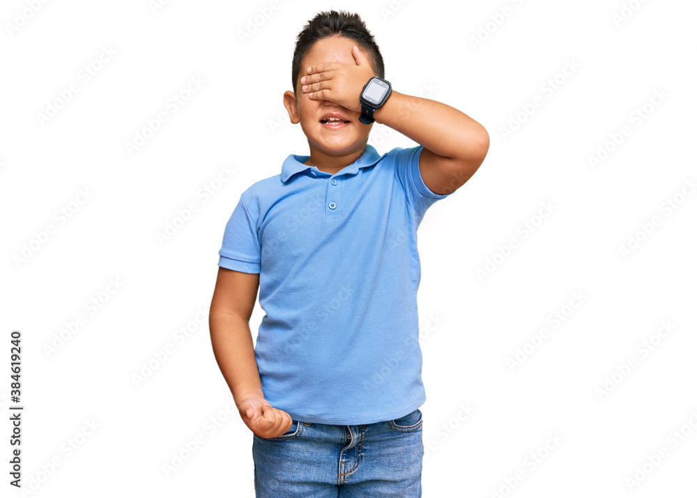 Little boy hispanic kid wearing casual clothes smiling and laughing with hand on face covering eyes for surprise. blind concept. Little boy hispanic kid wearing casual clothes smiling and laughing with hand on face covering eyes for surprise. blind concept.