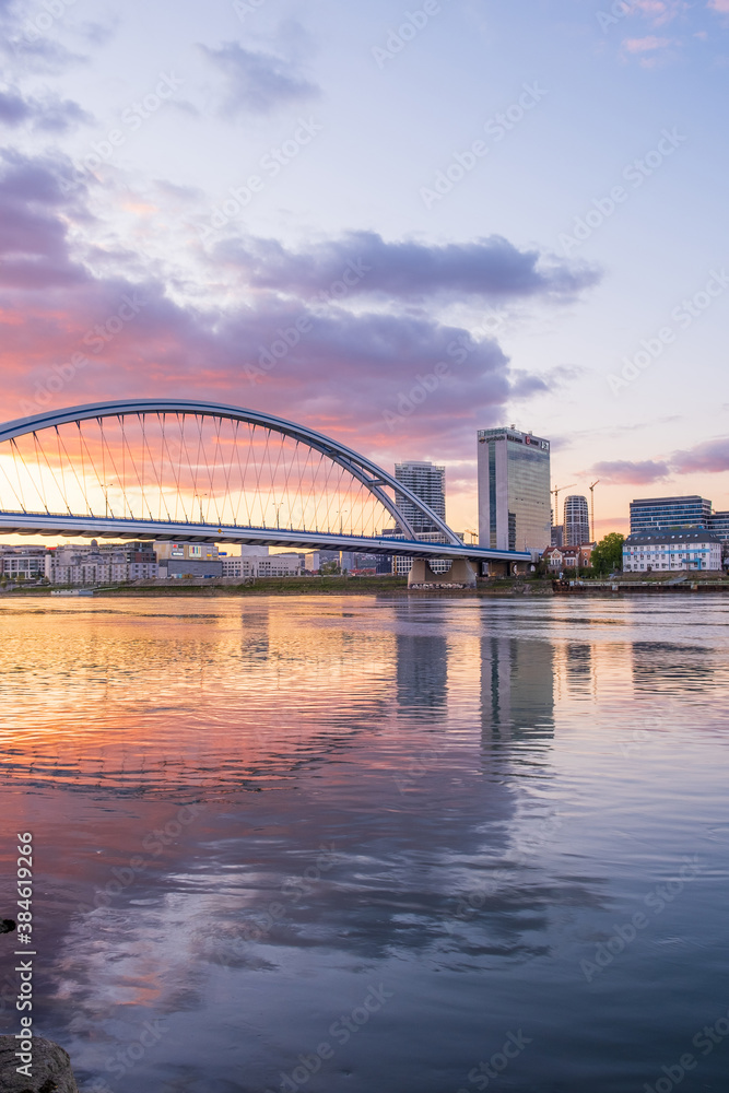 Naklejka premium 2020: Long exposure Apollo bridge over river Danube in Bratislava, Slovakia. Sunset, golden hour, dramatic skies. High rise buildings, travel destination