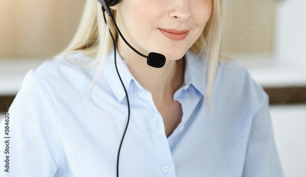 Blonde business woman sitting and communicated by headset in call center in sunny office. Concept of telesales business Blonde business woman sitting and communicated by headset in call center in sunny office. Concept of telesales business