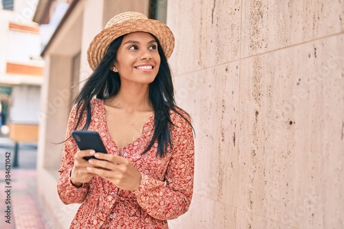 Young african american tourist woman on vacation smiling happy using smartphone at the city. © Krakenimages.com