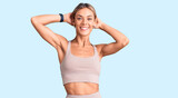 Beautiful caucasian woman wearing sportswear relaxing and stretching, arms and hands behind head and neck smiling happy