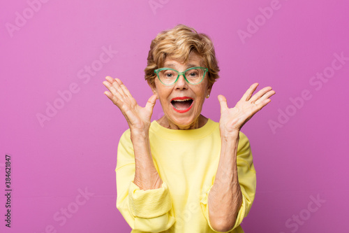 Fotografie old pretty woman looking happy and excited, shocked with an unexpected surprise