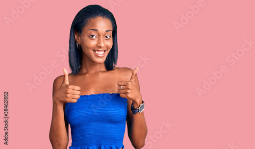 Young african american woman wearing casual summer clothes success sign doing positive gesture with hand, thumbs up smiling and happy. cheerful expression and winner gesture. photo