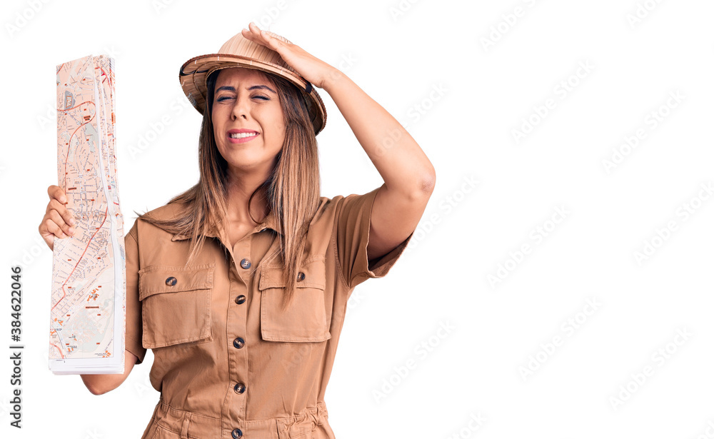 Young beautiful woman wearing explorer hat holding map stressed and frustrated with hand on head, surprised and angry face Young beautiful woman wearing explorer hat holding map stressed and frustrated with hand on head, surprised and angry face