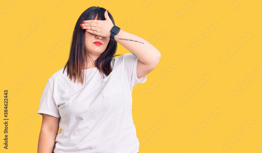 Young plus size woman wearing casual clothes covering eyes with hand, looking serious and sad. sightless, hiding and rejection concept Young plus size woman wearing casual clothes covering eyes with hand, looking serious and sad. sightless, hiding and rejection concept