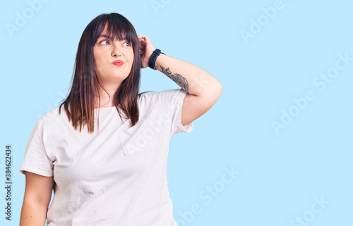 Young plus size woman wearing casual clothes confuse and wondering about question. uncertain with doubt, thinking with hand on head. pensive concept.