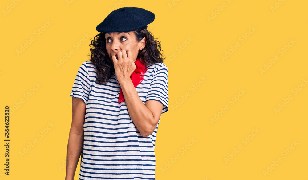 Middle age beautiful woman wearing french beret and scarf looking stressed and nervous with hands on mouth biting nails. anxiety problem. Middle age beautiful woman wearing french beret and scarf looking stressed and nervous with hands on mouth biting nails. anxiety problem.