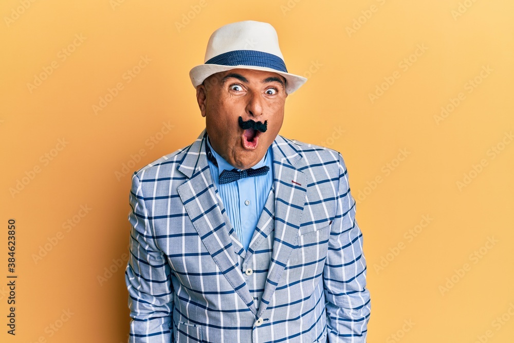 Mature middle east man with mustache wearing vintage and elegant fashion style afraid and shocked with surprise expression, fear and excited face.