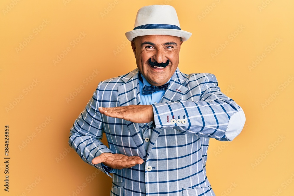 Mature middle east man with mustache wearing vintage and elegant fashion style gesturing with hands showing big and large size sign, measure symbol. smiling looking at the camera. measuring concept.