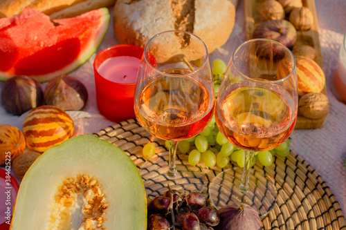 Picnic in the meadow.Wine, French baguette and fruits on the lawn at sunset.