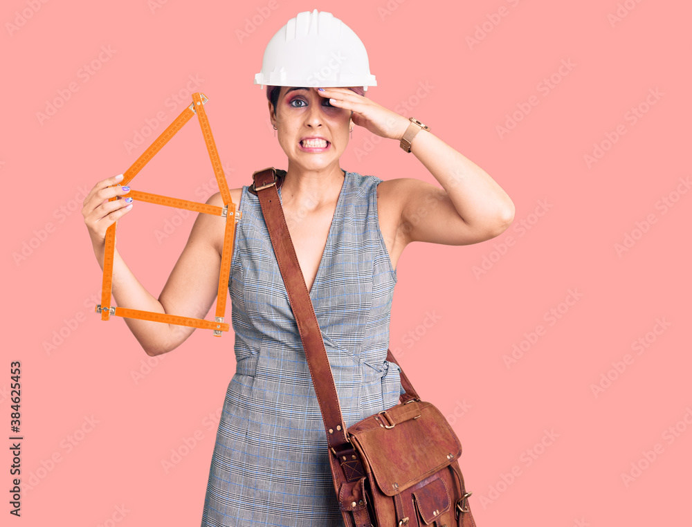 Young beautiful woman wearing architect hardhat holding build project stressed and frustrated with hand on head, surprised and angry face Young beautiful woman wearing architect hardhat holding build project stressed and frustrated with hand on head, surprised and angry face
