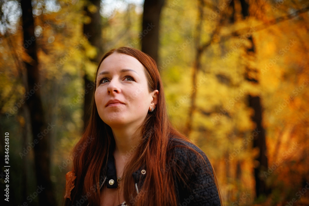 A red-haired girl in an autumn Park, against a background of yellow leaves. A red-haired girl in an autumn Park, against a background of yellow leaves.