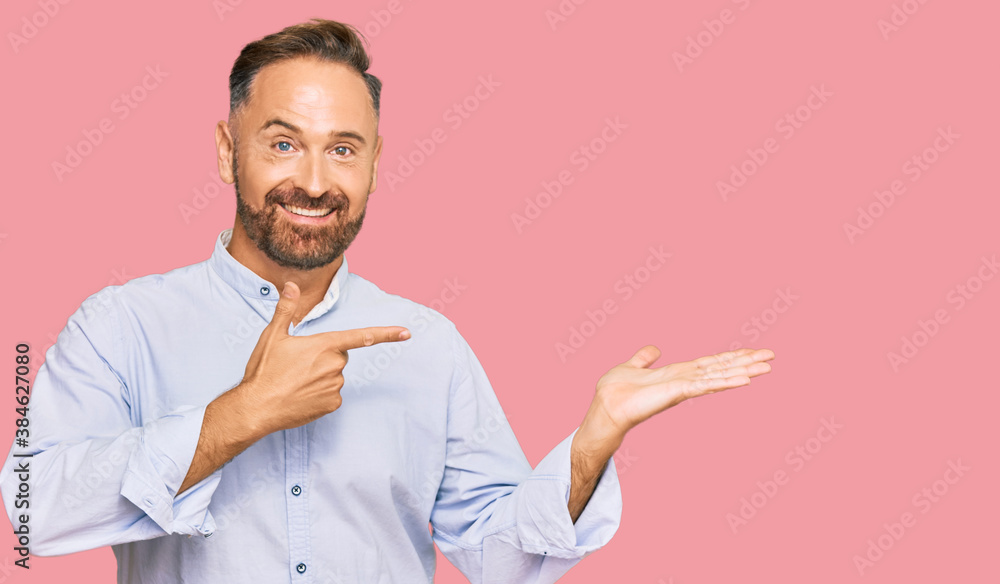 Handsome middle age man wearing business shirt amazed and smiling to the camera while presenting with hand and pointing with finger. Handsome middle age man wearing business shirt amazed and smiling to the camera while presenting with hand and pointing with finger.