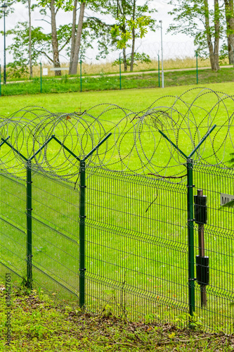 a metal fence of a military object with barbed wire