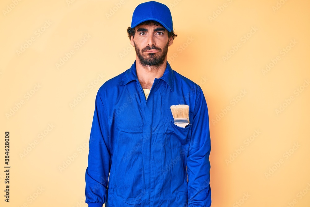 Handsome young man with curly hair and bear wearing builder jumpsuit uniform depressed and worry for distress, crying angry and afraid. sad expression.