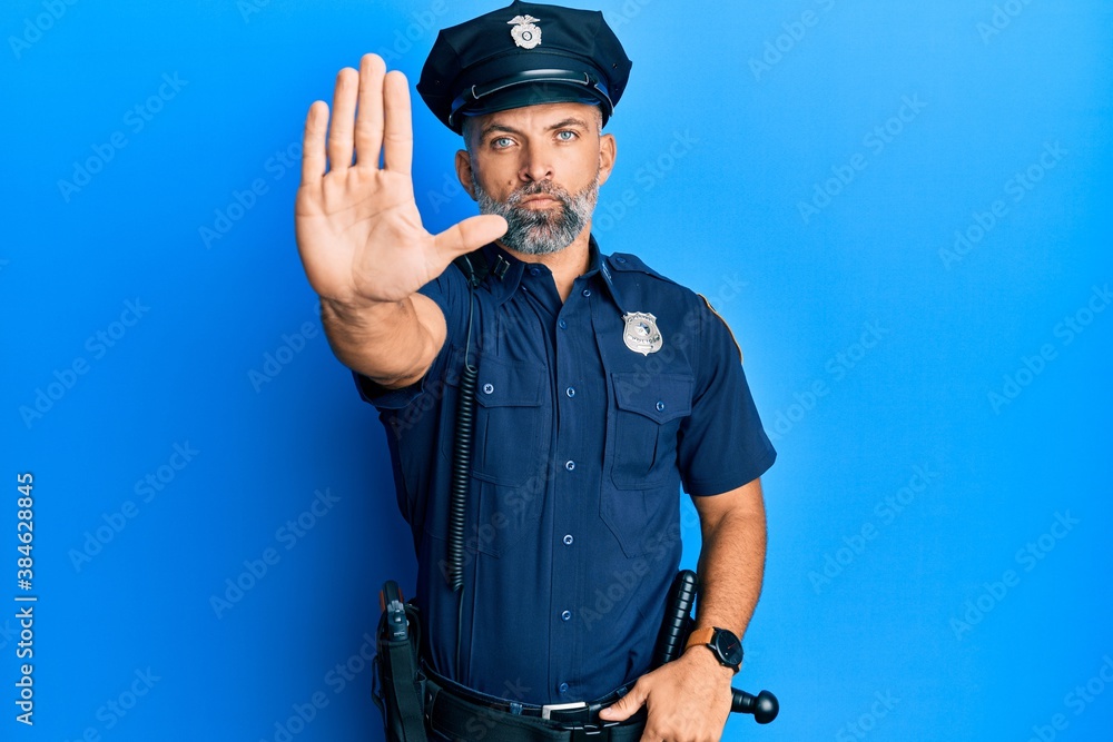 Middle age handsome man wearing police uniform doing stop sing with palm of the hand. warning expression with negative and serious gesture on the face. Middle age handsome man wearing police uniform doing stop sing with palm of the hand. warning expression with negative and serious gesture on the face.