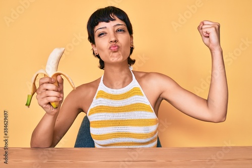 Brunette teenager girl eating banana as healthy snack looking at the camera blowing a kiss being lovely and sexy. love expression.