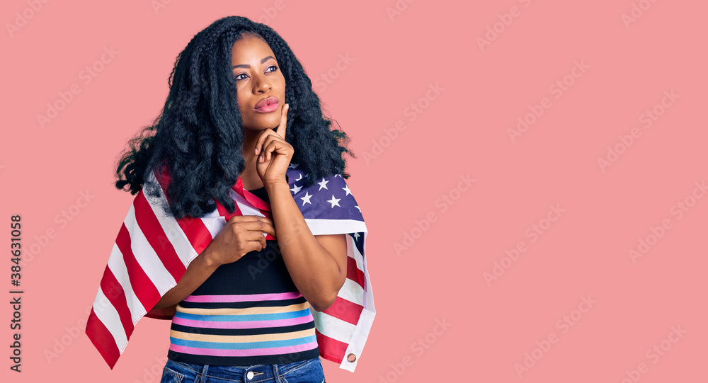 Beautiful african american woman holding united states flag serious face thinking about question with hand on chin, thoughtful about confusing idea Beautiful african american woman holding united states flag serious face thinking about question with hand on chin, thoughtful about confusing idea