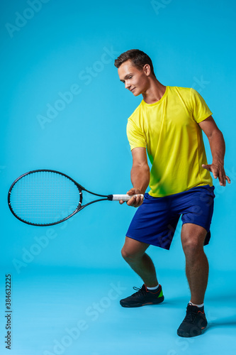 Full length studio portrait of a tennis player man on blue background © fotofabrika
