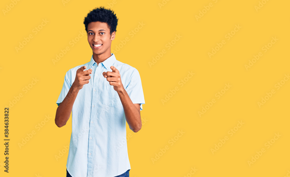 Young african american man wearing casual clothes pointing fingers to camera with happy and funny face. good energy and vibes. Young african american man wearing casual clothes pointing fingers to camera with happy and funny face. good energy and vibes.