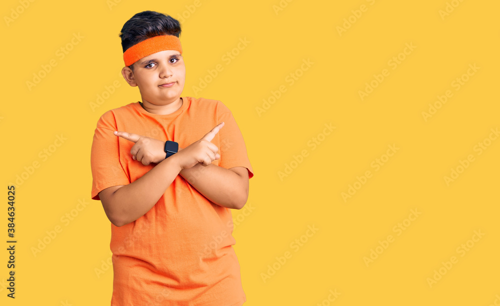Little boy kid wearing sportswear pointing to both sides with fingers, different direction disagree