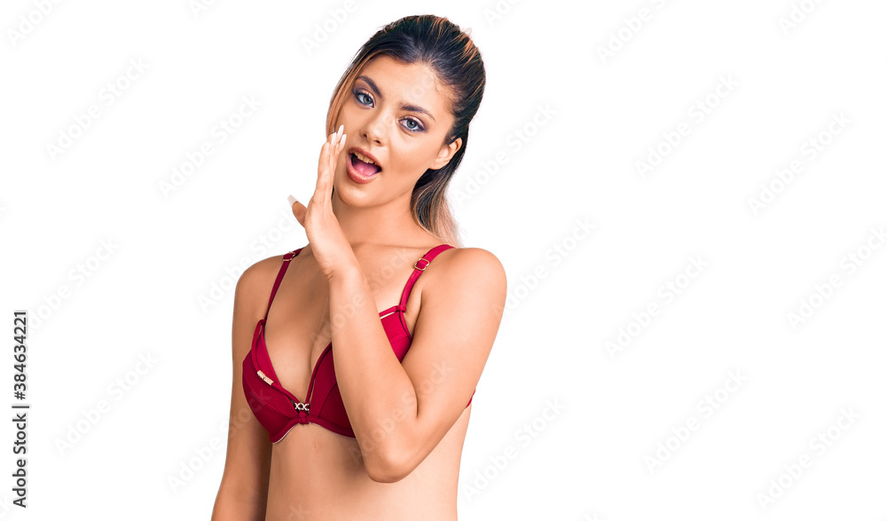 Fototapeta premium Young beautiful woman wearing bikini hand on mouth telling secret rumor, whispering malicious talk conversation