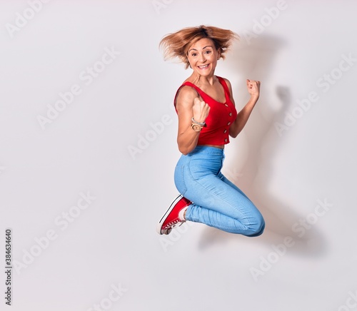 Fototapeta Naklejka Na Ścianę i Meble -  Young beautiful woman wearing casual clothes smiling happy. Jumping with smile on face doing winner gesture with thumbs up over isolated white background